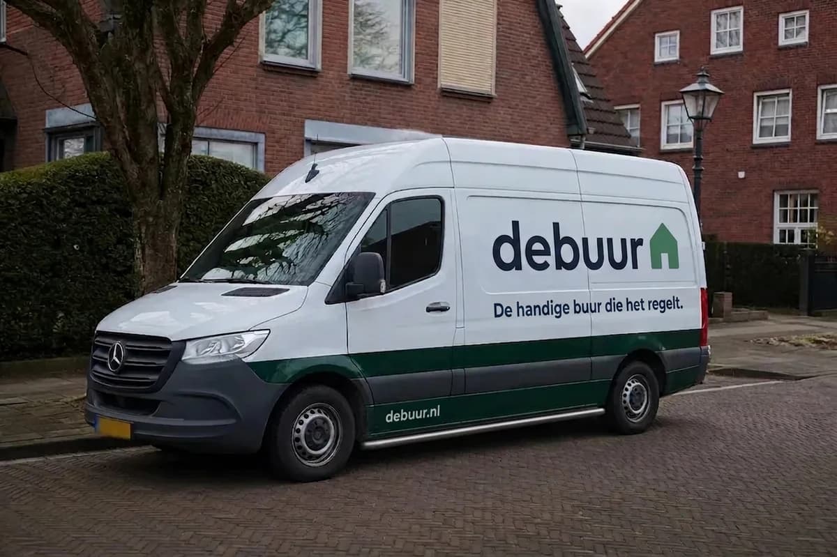 Witte Debuur-bestelbus met een groen-grijze streep geparkeerd aan een straat met rijtjeshuizen.