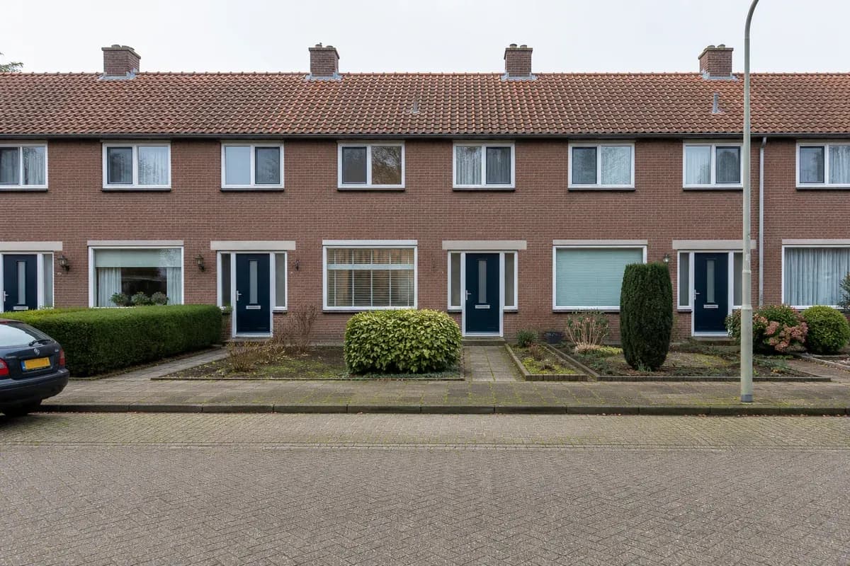 Rij identieke huurwoningen met kleine voortuinen aan een straat.